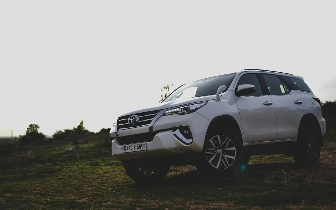 Toyota Fortuner สีขาวจอดบนทุ่งหญ้า