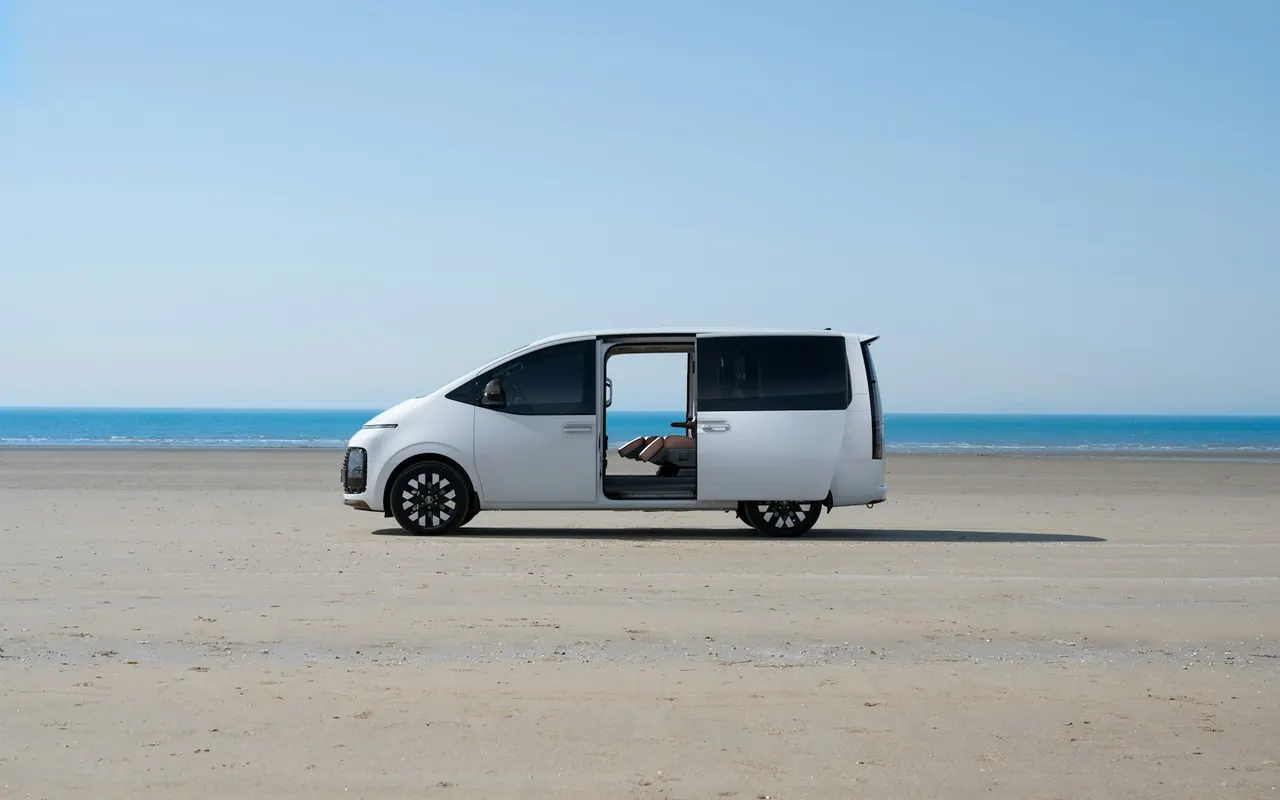 Hyundai Staria สีขาวเปิดประตูข้างริมชายหาด