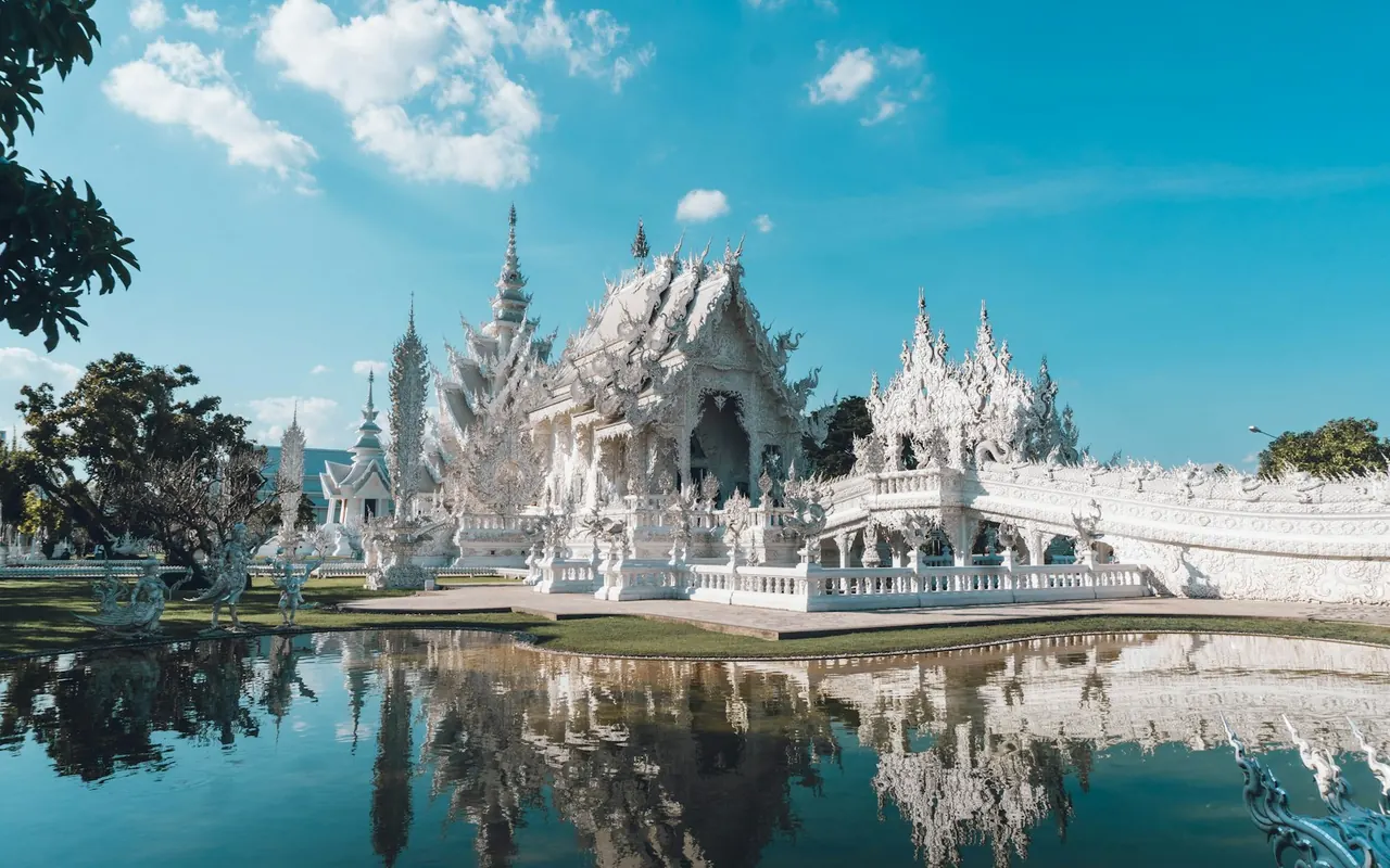 วัดร่องขุ่นสีขาวสะท้อนเงาในสระน้ำ